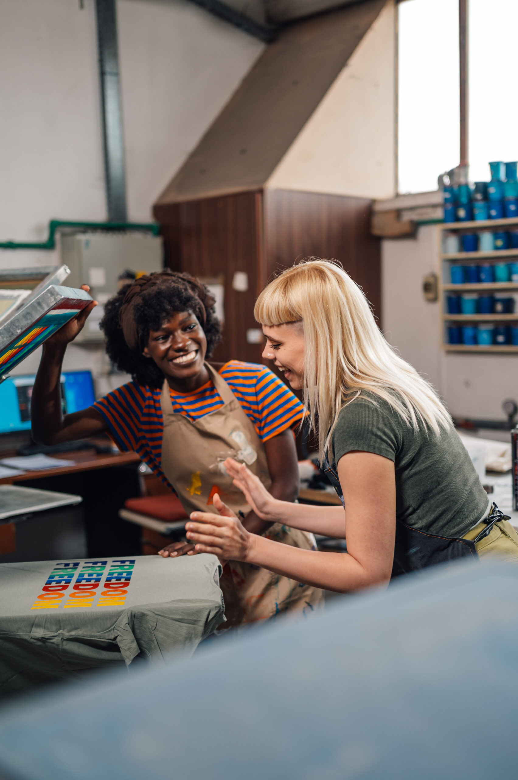 Interracial graphic technicians looking at silk screen printed t-shirt