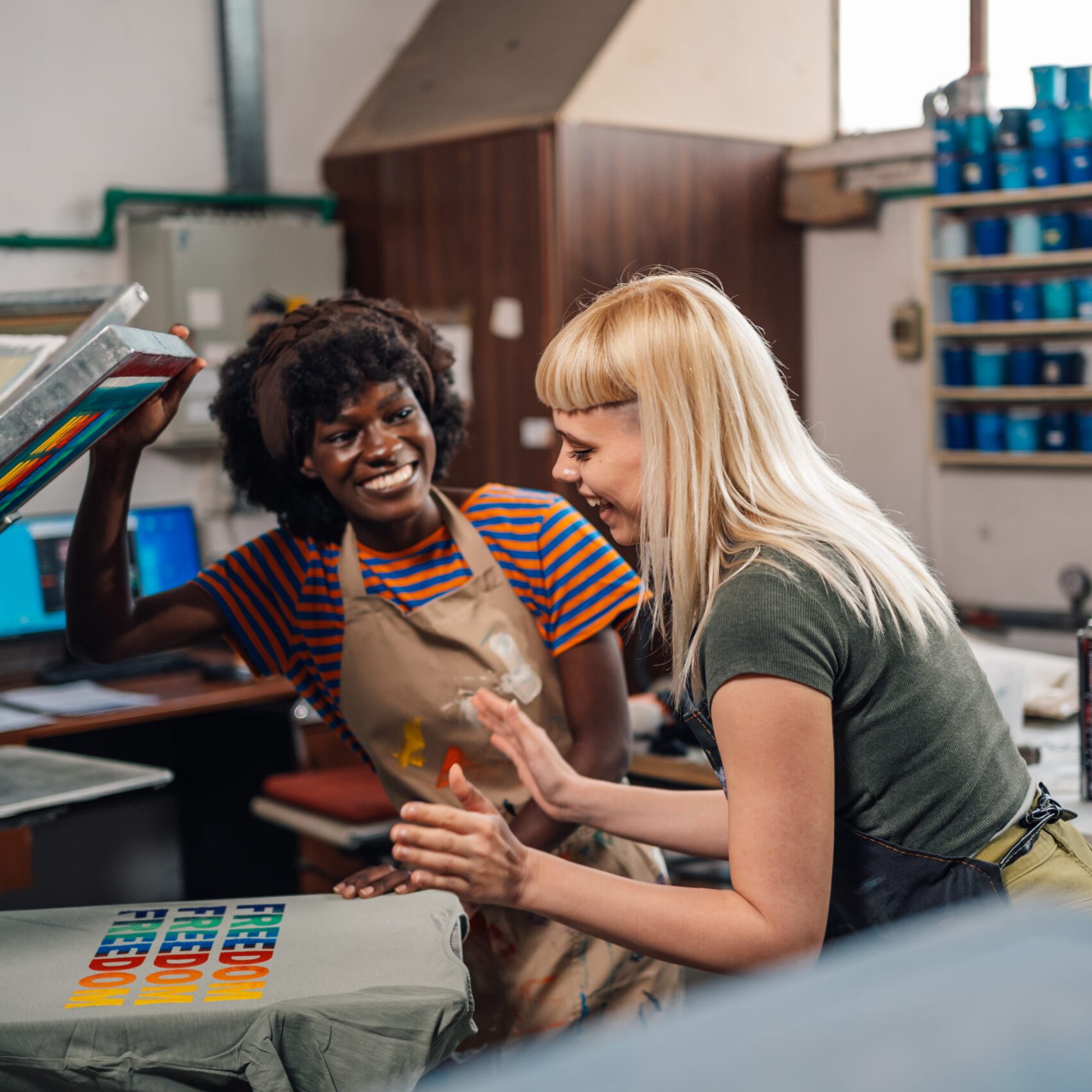 Interracial graphic technicians looking at silk screen printed t-shirt